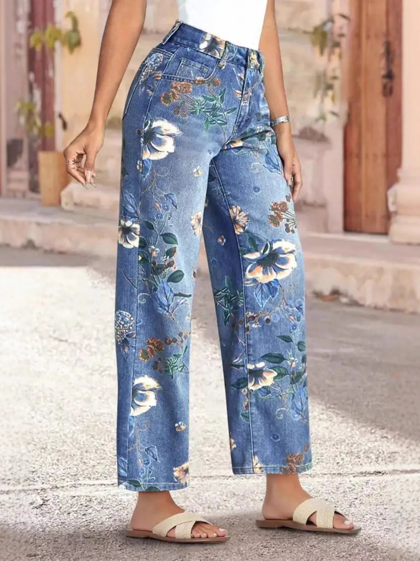 NEWYORKLISTED STYLE COLLECTION: Person wearing floral-patterned blue jeans standing on a stone pavement.