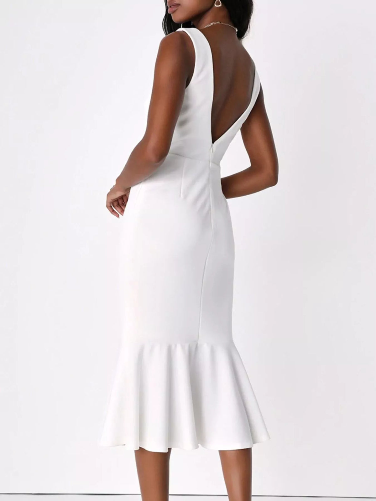 NEWYORKLISTED STYLE COLLECTION: A woman modeling a white sleeveless midi dress from the back, featuring a deep open back, fitted silhouette, and flared ruffled hem, set against a plain white studio background.