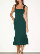 NEWYORKLISTED STYLE COLLECTION: A woman modeling a dark green sleeveless midi dress with a square neckline, fitted silhouette, and flared ruffled hem against a plain white studio background.