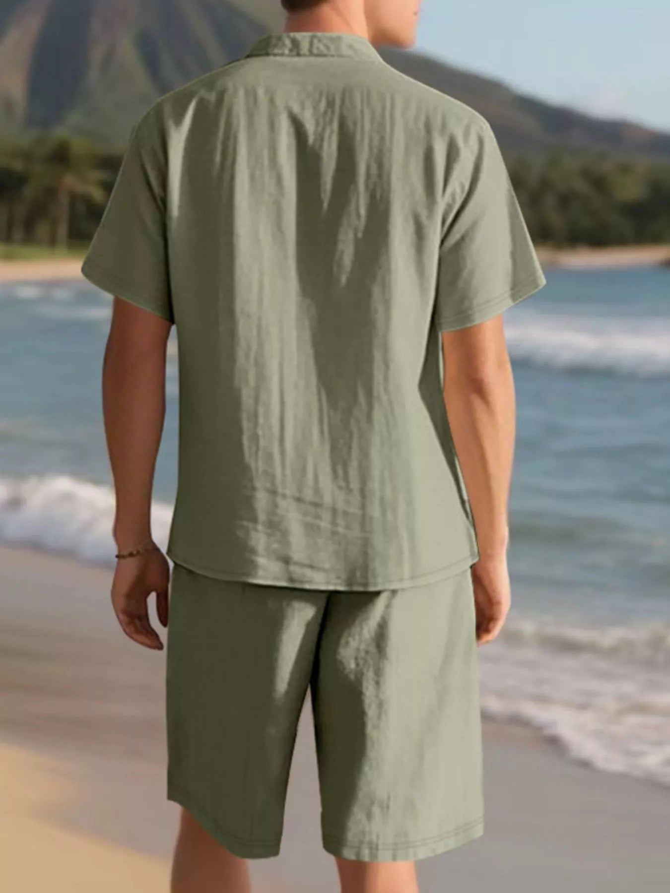 NEWYORKLISTED ATLAS MEN'S COLLECTION: Person wearing a green shirt and shorts standing on a beach with mountains in the background
