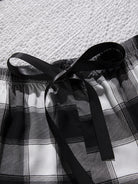 Plaid shorts with a black ribbon on a textured white background