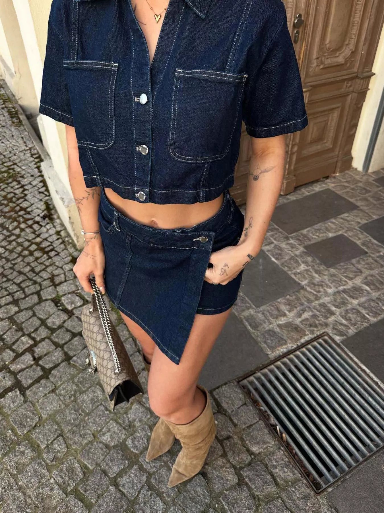 NEWYORKLISTED STYLE COLLECTION: Person wearing a denim outfit with a cropped shirt and shorts, standing on a street.
