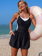 NEWYORKLISTED EDEN COLLECTION: Woman in a black and white swimsuit with a pink inflatable ring on a beach.
