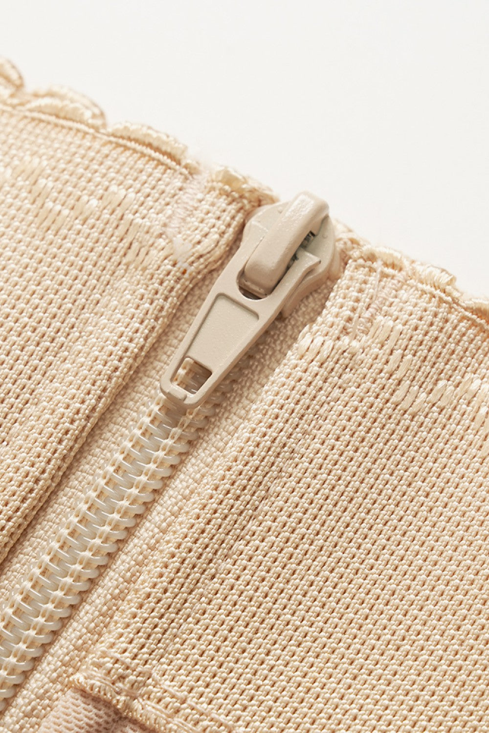 NEWYORKLISTED Intimate Apparel: Close-up of a beige zipper on a textured fabric background