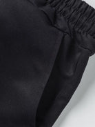 NEWYORKLISTED ATLAS MEN'S COLLECTION: Close-up of black pants with an elastic waistband on a light gray background