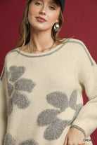 NEWYORKLISTED STYLE COLLECTION: Woman wearing a cream sweater with gray floral patterns against a red background