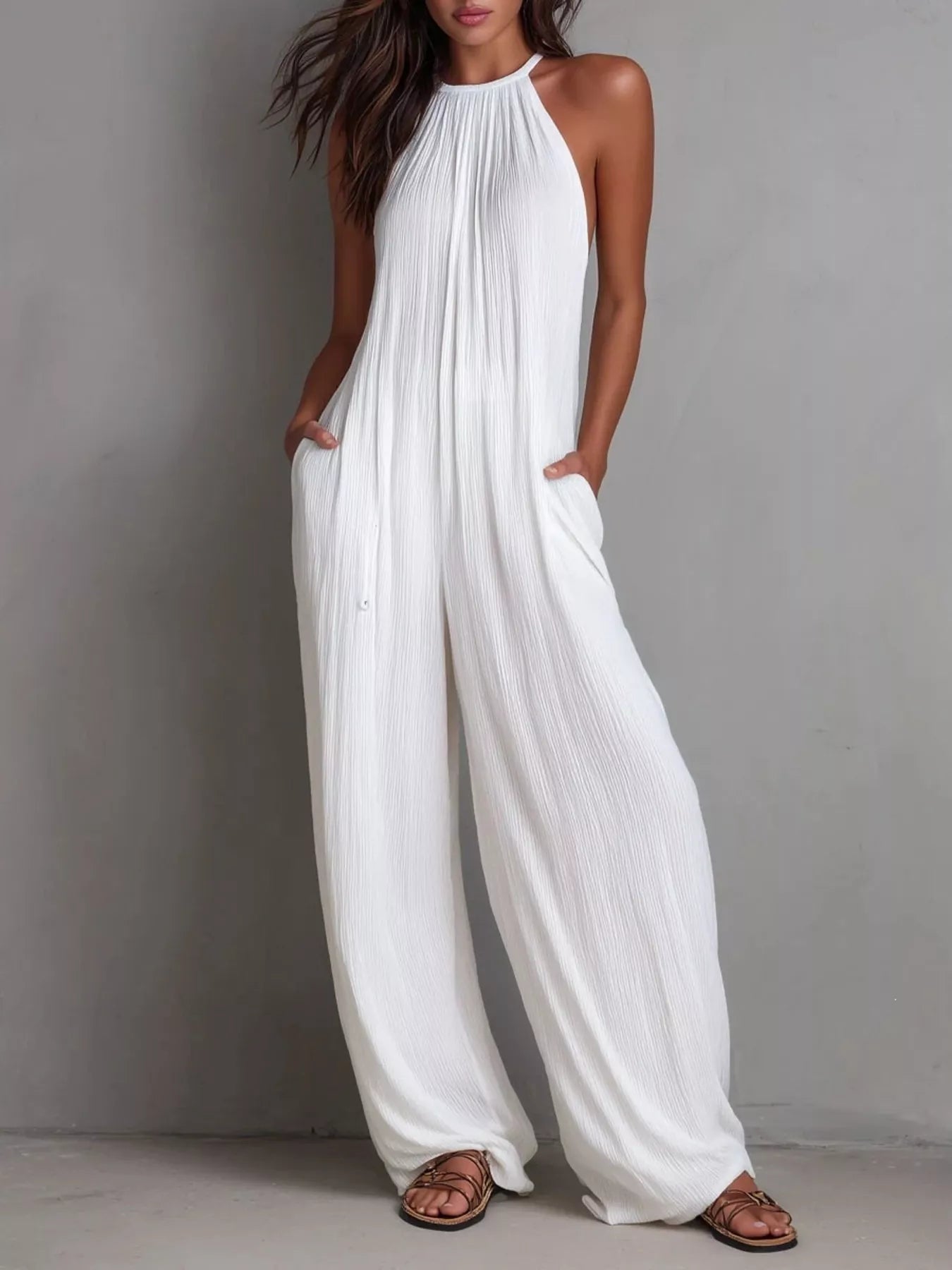 NEWYORKLISTED STYLE COLLECTION: Woman wearing a white halter neck jumpsuit against a gray background