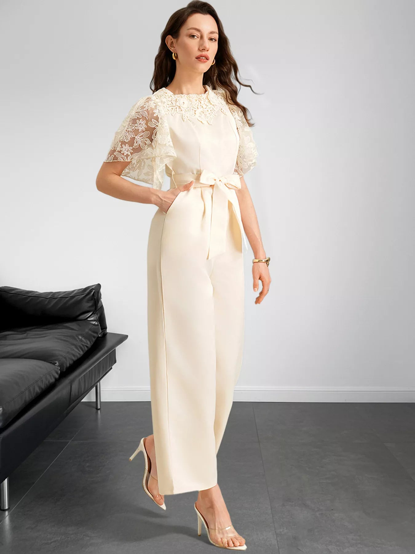 NEWYORKLISTED STYLE COLLECTION: Woman wearing a cream-colored dress with lace sleeves in a minimalistic room.