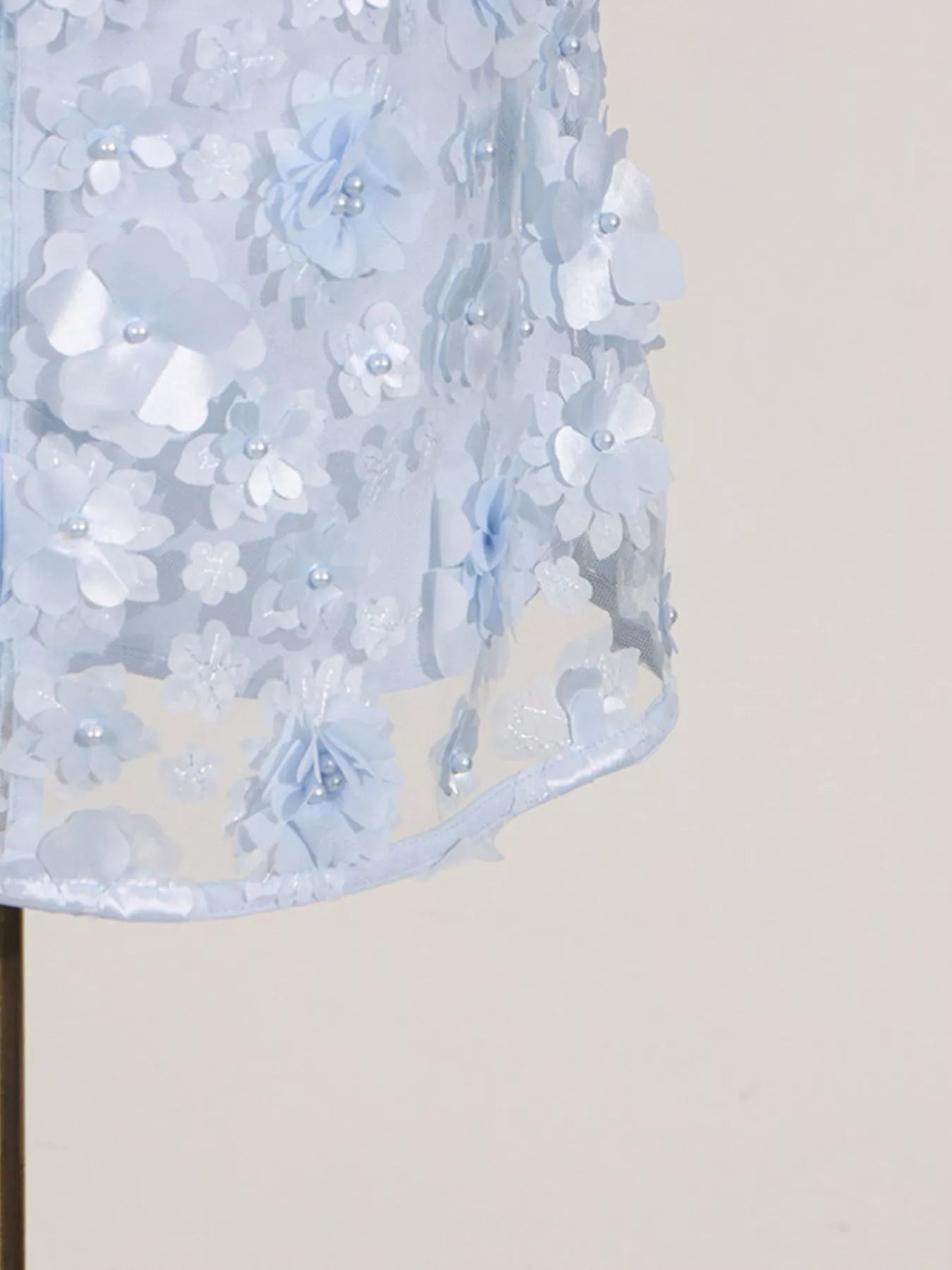 NEWYORKLISTED STYLE COLLECTION: Close-up of a light blue floral dress on a mannequin against a beige background