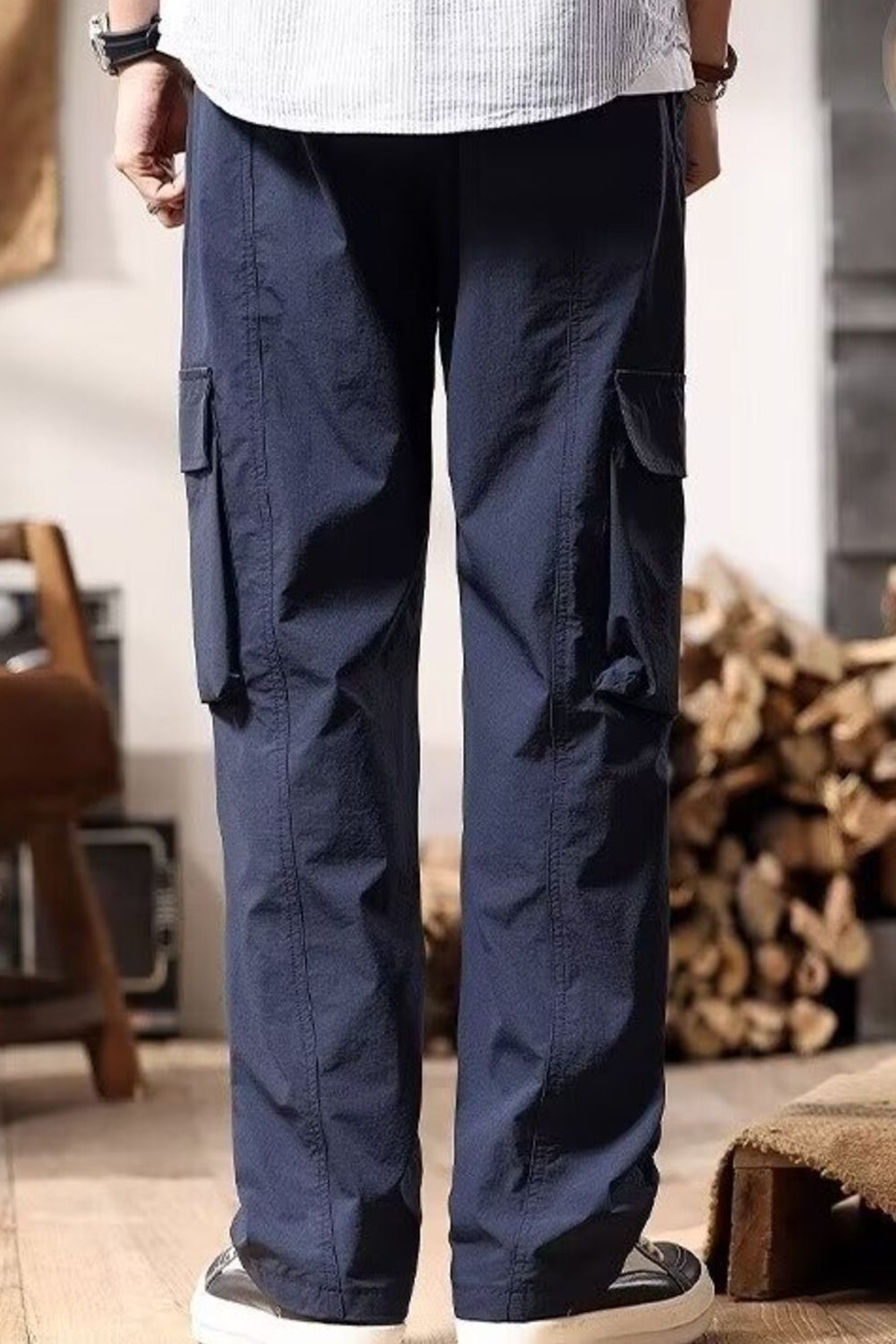 NEWYORKLISTED ATLAS MEN's COLLECTION: Person wearing navy cargo pants in an indoor setting with wooden logs in the background