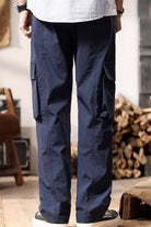 NEWYORKLISTED ATLAS MEN's COLLECTION: Person wearing navy cargo pants in an indoor setting with wooden logs in the background