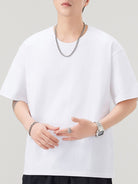 NEWYORKLISTED ATLAS MEN"S COLLECTION: Person wearing a white t-shirt with minimal accessories on a plain background
