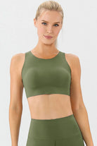 NEWYORKLISTED ACTIVEWEAR COLLECTION: Woman wearing an olive green sports bra and leggings on a white background
