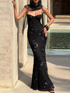 NEWYORKLISTED STYLE COLLECTION: Woman in a black lace evening gown standing by a stone wall.