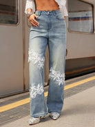 NEWYORKLISTED STYLE COLLECTION: Person wearing blue jeans with floral embroidery on a train platform.