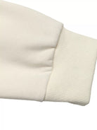 NEWYORKLISTED STYLE COLLECTION: Close-up of a beige sweater sleeve on a white background
