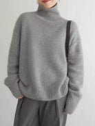 NEWYORKLISTED STYLE COLLECTION: Person wearing a gray turtleneck sweater and pants on a plain background