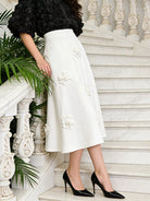 NEWYORKLISTED STYLE COLLECTION: Floral Embellished Midi Skirt -Person wearing a white skirt with floral embroidery on a marble staircase.