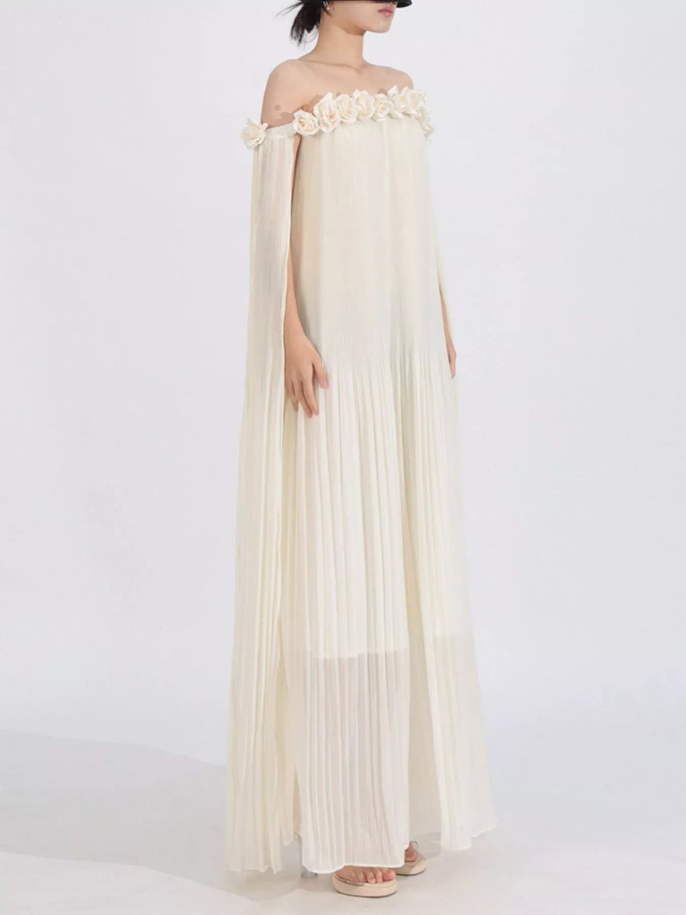 NEWYORKLISTED STYLE COLLECTION: Woman wearing a flowing off-shoulder dress with floral details on a white background