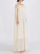 NEWYORKLISTED STYLE COLLECTION: Woman wearing a flowing off-shoulder dress with floral details on a white background