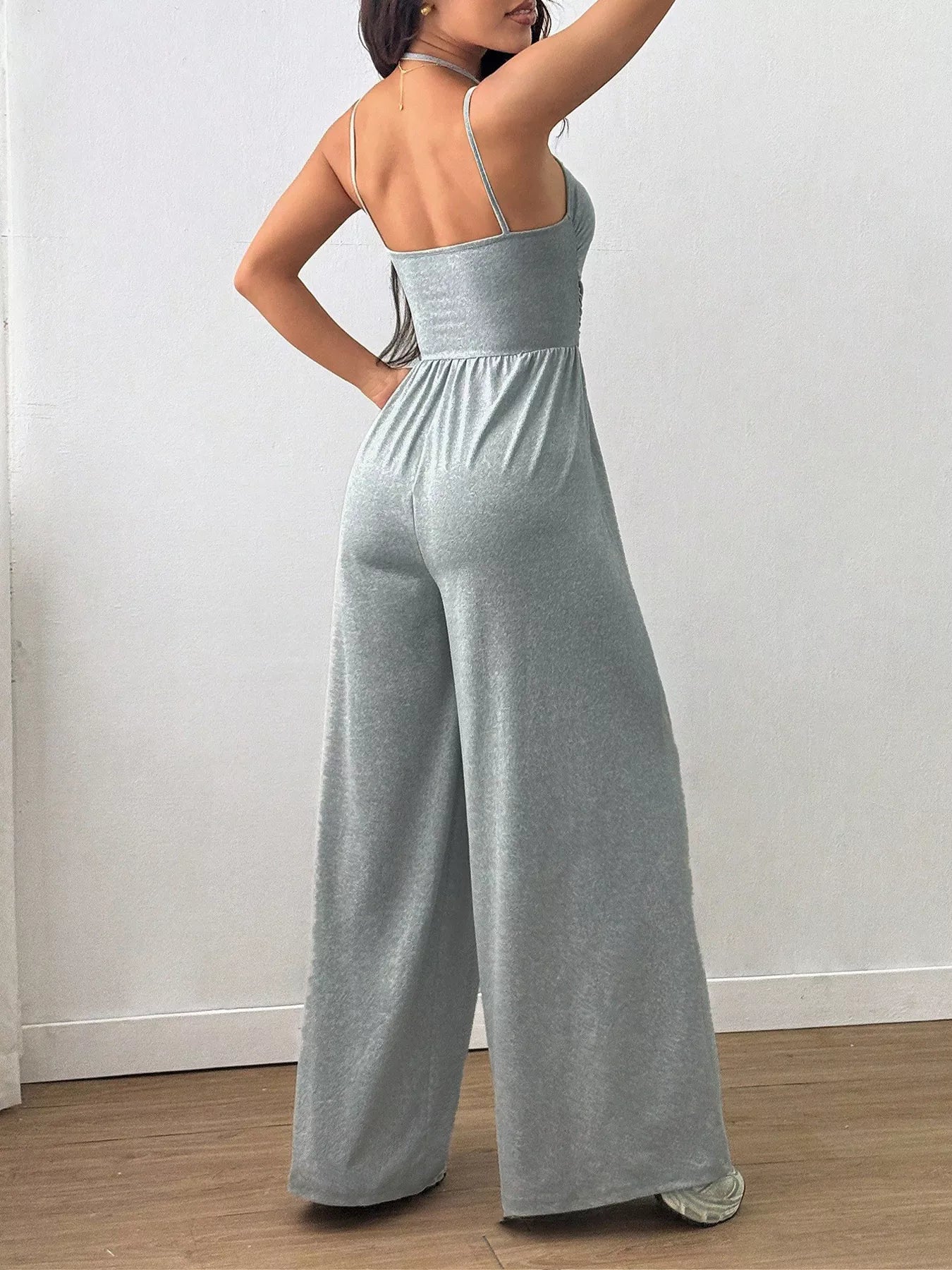 NEWYORKLISTED Comfort Collection: Person wearing a gray jumpsuit against a white wall.
