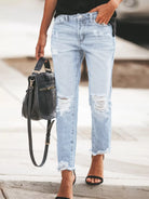 NEWYORKLISTED STYLE COLLECTION: Person wearing light blue distressed jeans holding a black handbag.