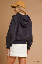 NEWYORKLISTED STYLE COLLECTION: Person wearing a dark hoodie and white shorts with a beige cap on a brown background