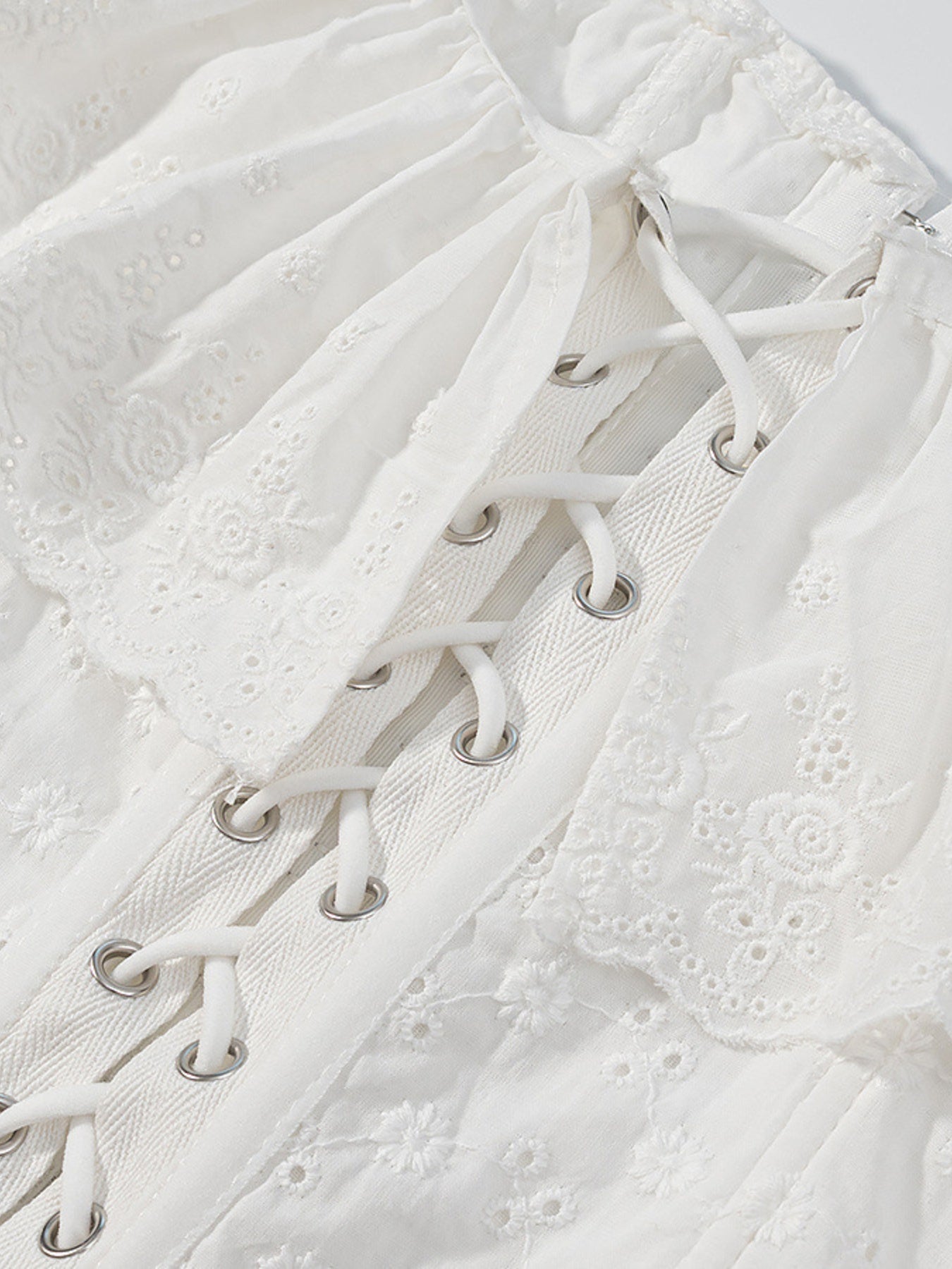 NEWYORKLISTED STYLE COLLECTION: Close-up of a white lace-up garment with intricate detailing.