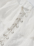 NEWYORKLISTED STYLE COLLECTION: Close-up of a white lace-up garment with intricate detailing.