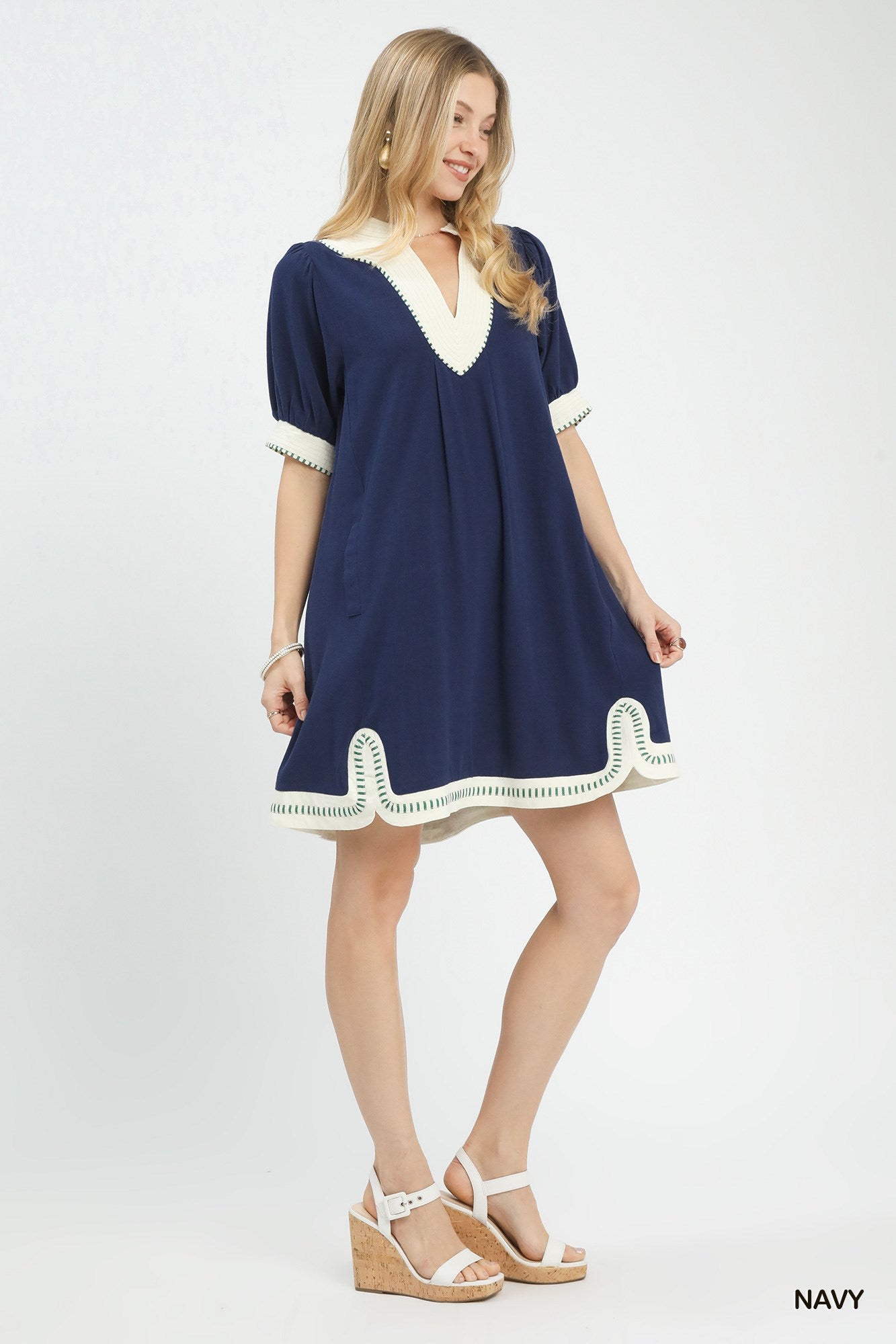 NEWYORKLISTED STYLE COLLECTION: Woman wearing a navy dress with white trim on a white background