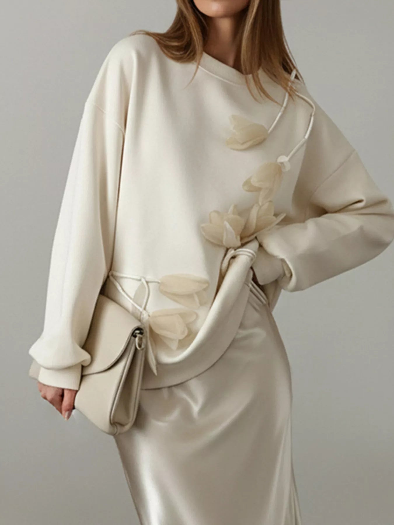 NEWYORKLISTED STYLE COLLECTION: Woman wearing a beige outfit with a matching handbag against a neutral background