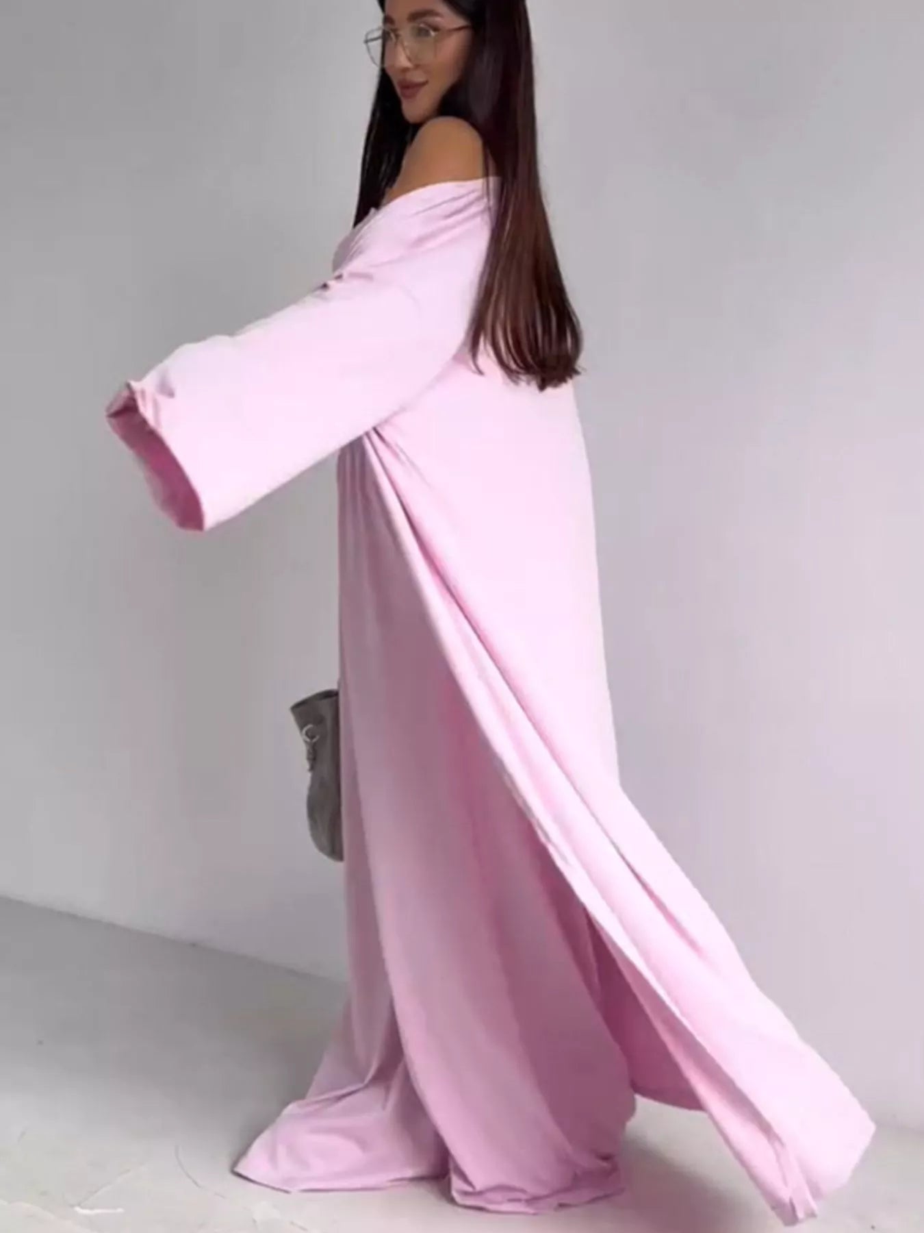 NEWYORKLISTED COMFORT COLLECTION: Woman wearing a long pink off-shoulder dress against a plain background