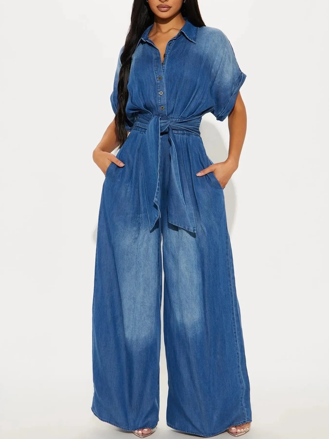 NEWYORKLISTED STYLE COLLECTION: Woman wearing a blue denim jumpsuit on a white background