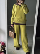 NEWYORKLISTED Comfort Collection: Person wearing a green sweater and pants holding a brown handbag, standing in front of a mirror.