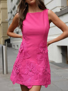NEWYORKLISTED STYLE COLLECTION: Woman wearing a bright pink dress with floral embellishments on a city street.