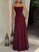 NEWYORKLISTED STYLE COLLECTION: Woman wearing a burgundy lace dress standing indoors with decorative lanterns and a plant in the background.