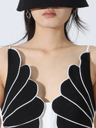 NEWYORKLISTED: Person wearing a black and white sleeveless top with unique design on a white background