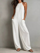 NEWYORKLISTED STYLE COLLECTION: Woman wearing a white jumpsuit against a plain background