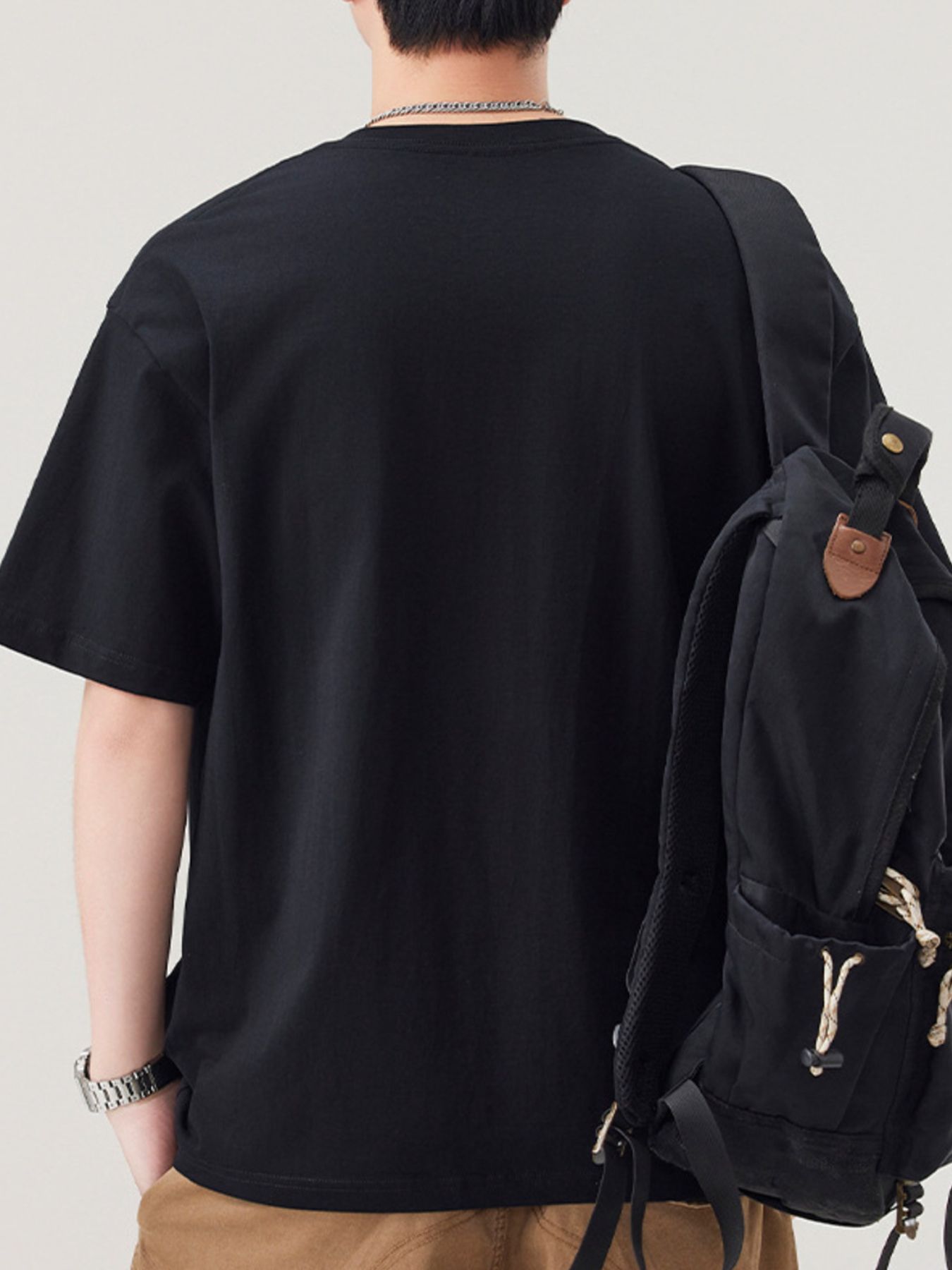 NEWYORKLISTED ATLAS MEN"S COLLECTION: Person wearing a black t-shirt and carrying a black backpack on a plain background