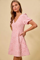 NEWYORKLISTED STYLE COLLECTION: Woman wearing a pink floral dress against a beige background