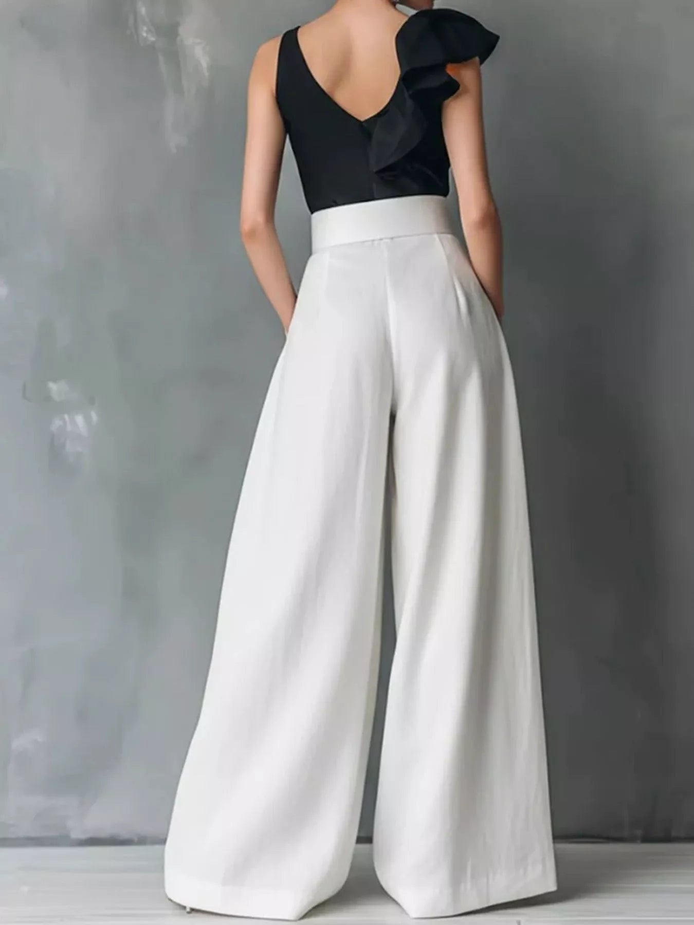 NEWYORKLISTED STYLE COLLECTION: Person wearing a black top and white wide-leg pants against a gray background