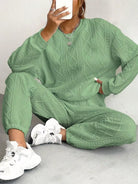 NEWYORKLISTED COMFORT COLLECTION: Person wearing a green cable knit outfit with white sneakers on a light gray background