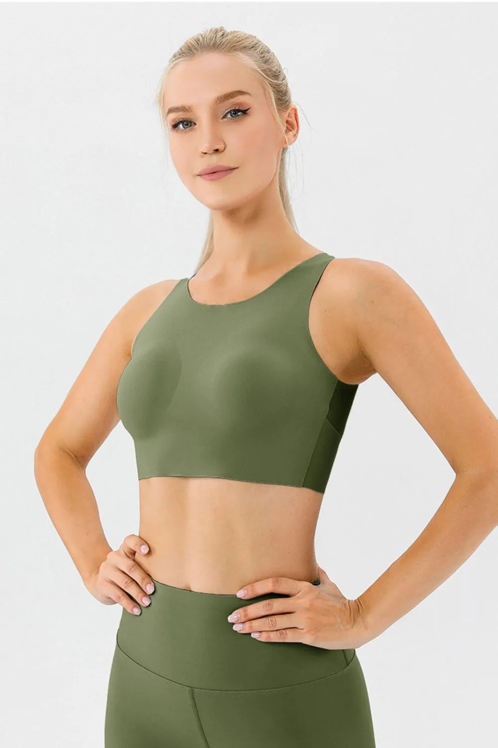 NEWYORKLISTED ACTIVEWEAR COLLECTION: Woman wearing a green sports bra and leggings on a light gray background