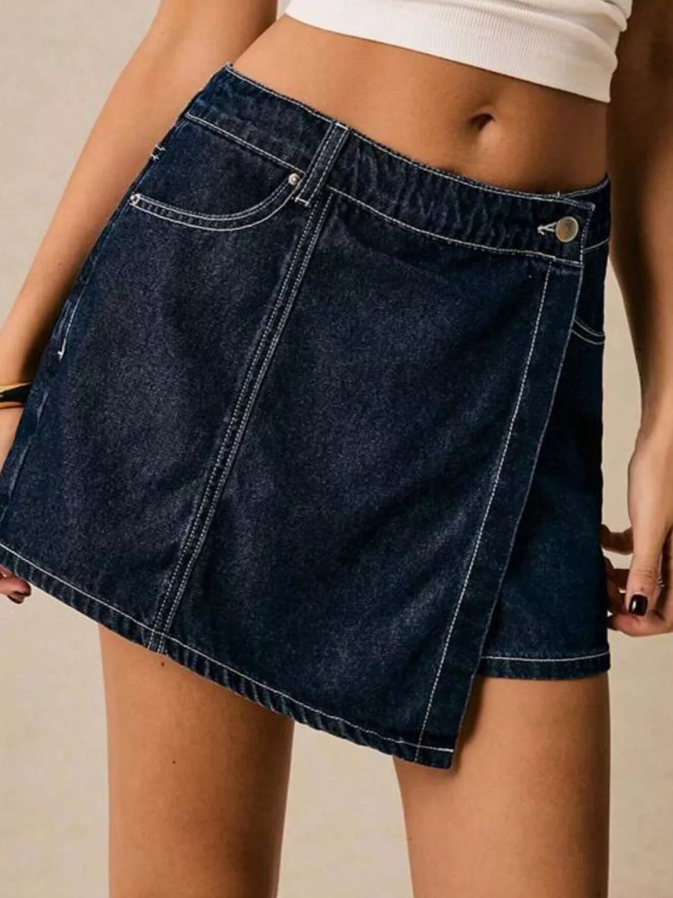 NEWYORKLISTED STYLE COLLECTION: Person wearing a dark blue denim skirt on a neutral background