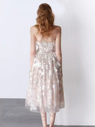 NEWYORKLISTED STYLE COLLECTION: Woman wearing a strapless floral dress against a white background