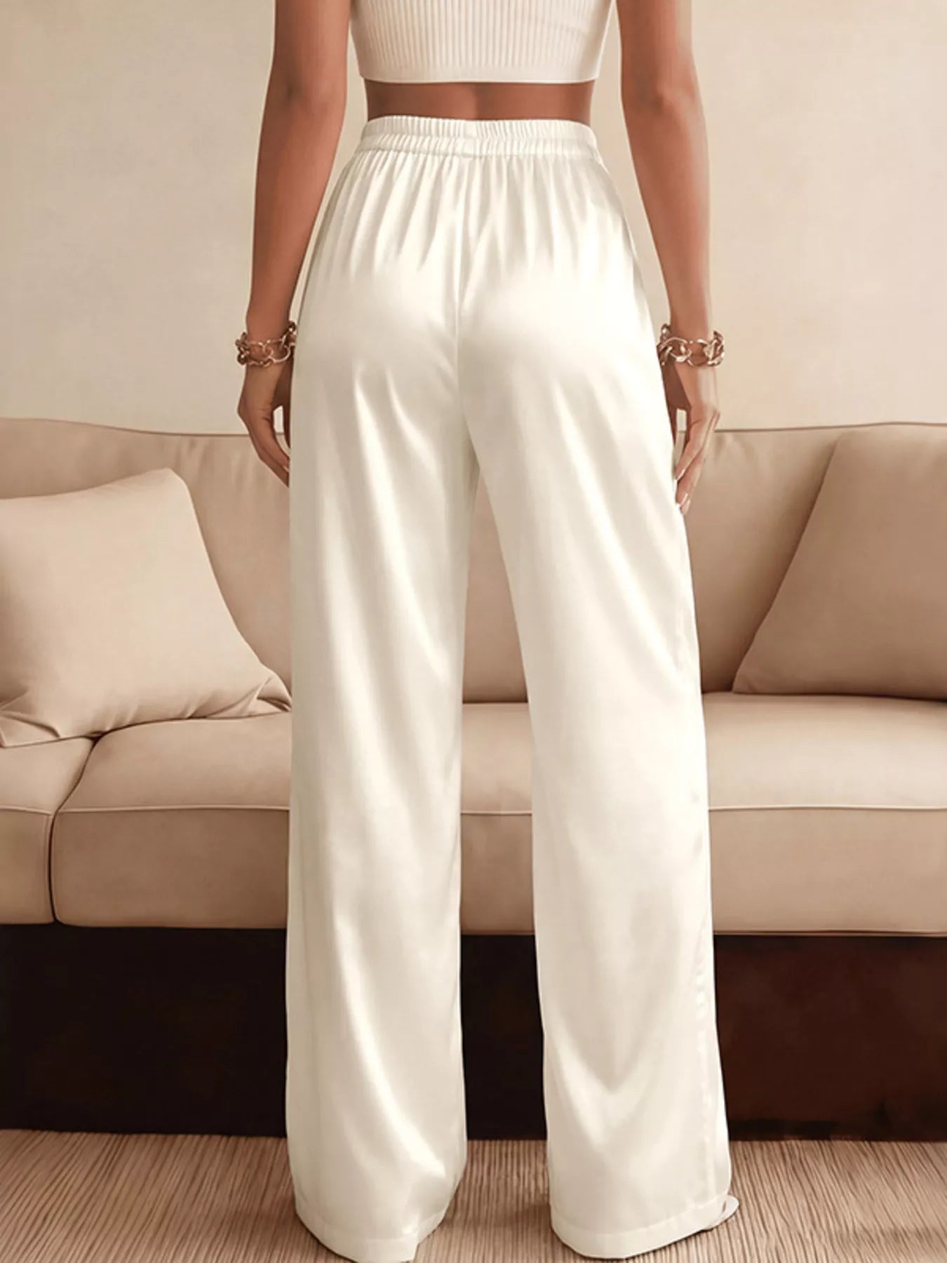 NEWYORKLISTED STYLE COLLECTION: Person wearing white pants standing in front of a beige sofa.