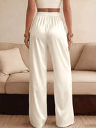 NEWYORKLISTED STYLE COLLECTION: Person wearing white pants standing in front of a beige sofa.