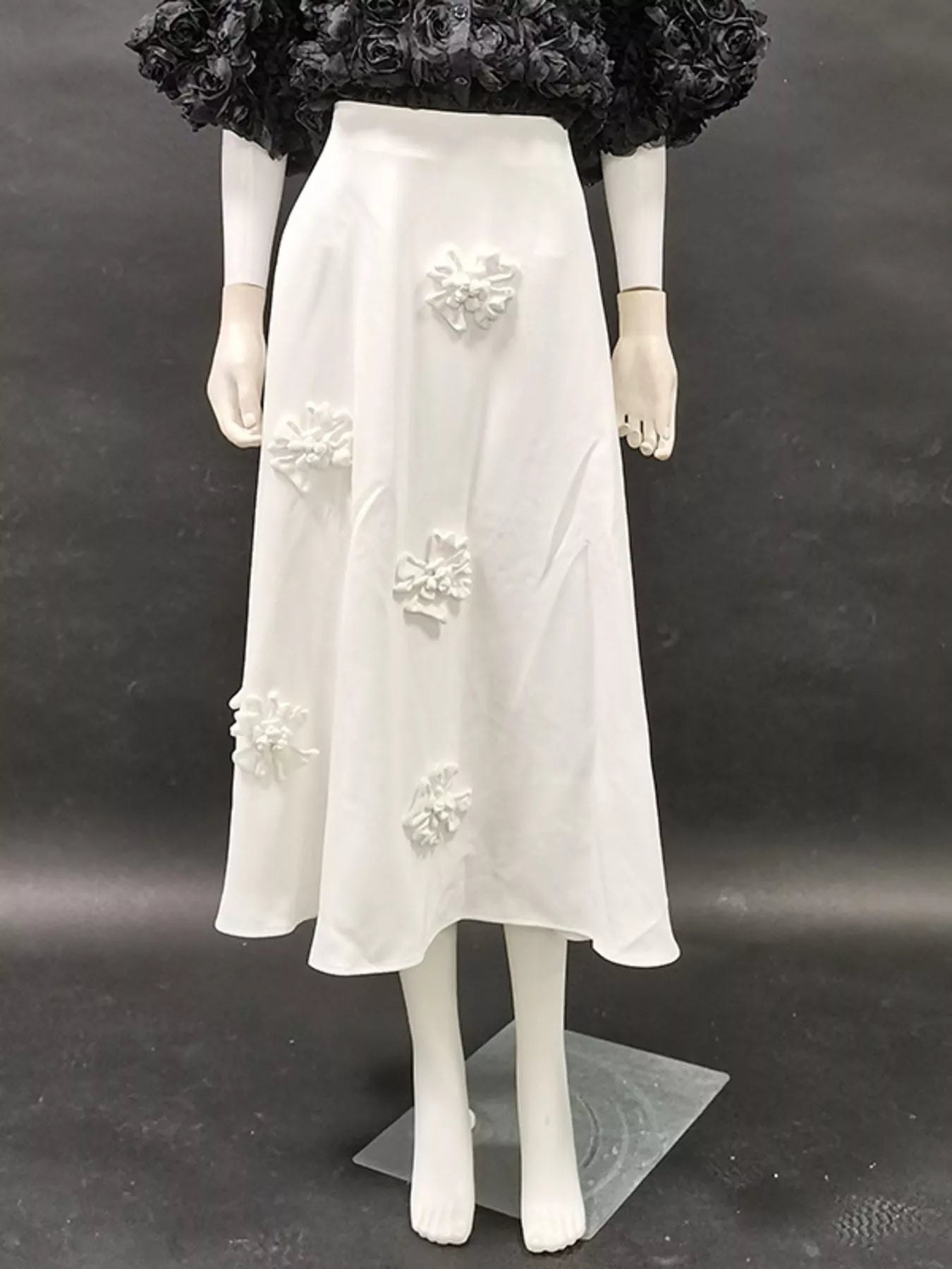 NEWYORKLISTED STYLE COLLECTION: Mannequin wearing a white dress with floral embellishments on a dark background