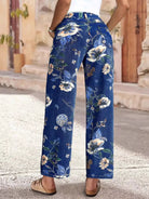 NEWYORKLISTED STYLE COLLECTION: Blue floral pants worn by a person on a stone pavement.