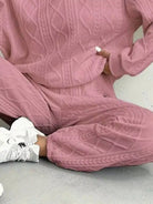 NEWYORKLISTED COMFORT COLLECTION: Person wearing a pink textured tracksuit sitting on a light gray floor.